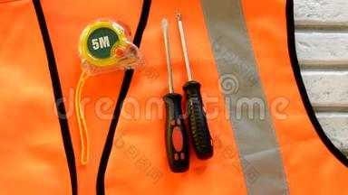 橙色施工背心上有螺丝刀、施工工具、量尺、扳手、<strong>劳动节</strong>概念